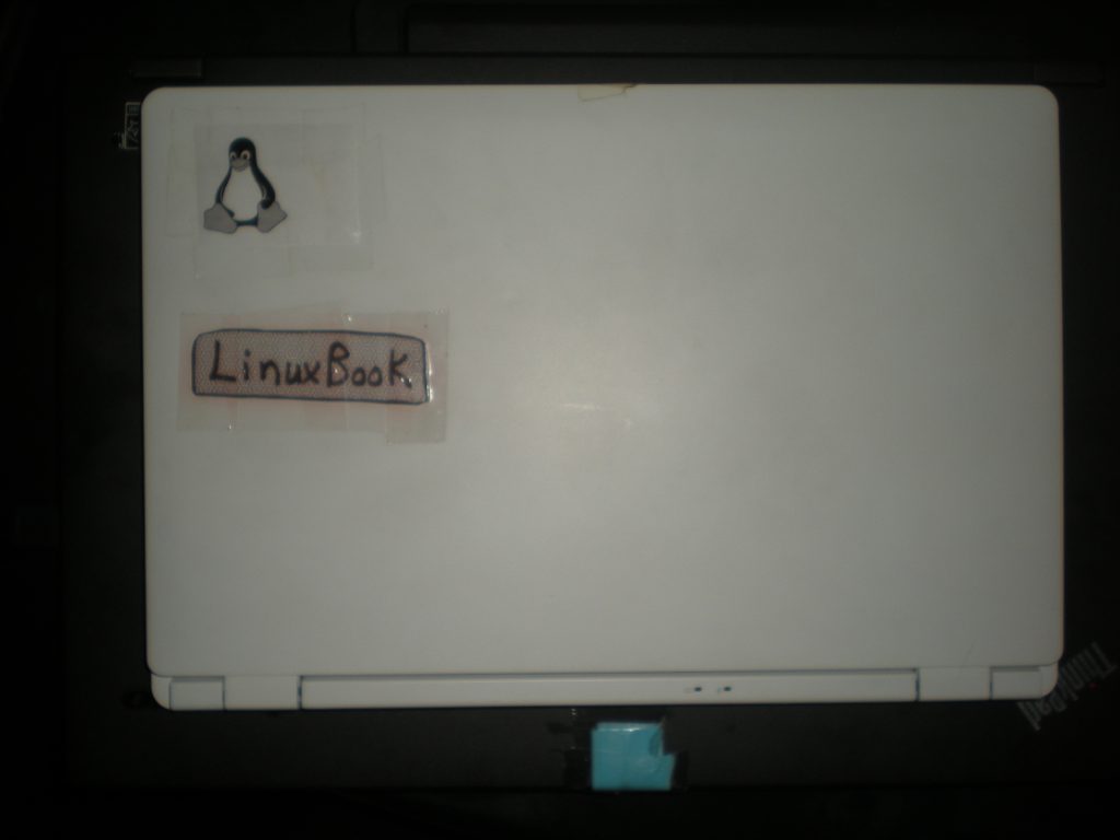 My 2014 LinuxBook, formerly known as Chromebook, displays its custom Tux logo and name. It's also sitting on top of my 2014 Lenovo ThinkPad W540 laptop.