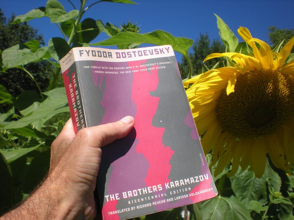 Image of the novel, "The Brothers Karamazov" (1880) by Fyodor Dostoevsky (1821–1881). Back ground is a garden with sunflowers and blue sky.